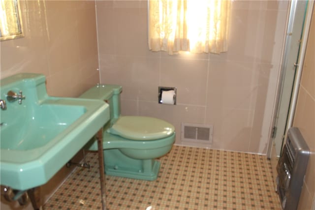 bathroom featuring tile walls and toilet