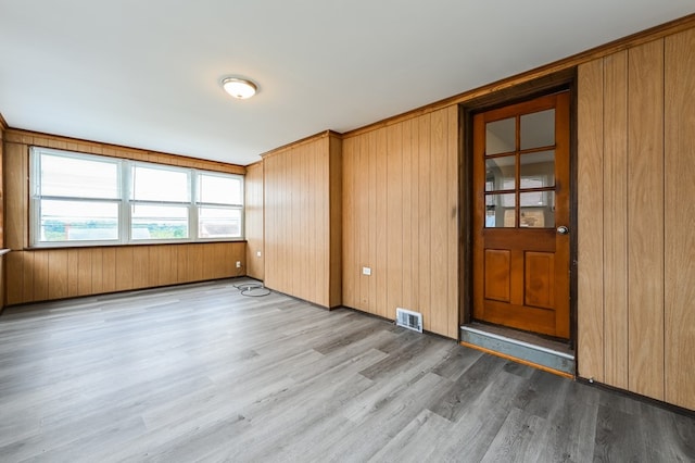 empty room featuring wooden walls and light wood-type flooring