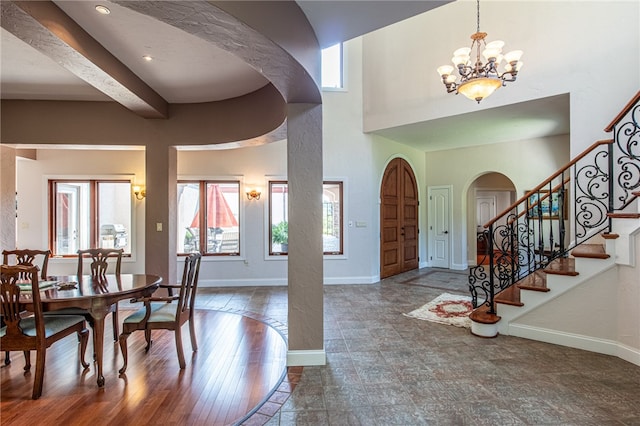 foyer with an inviting chandelier, a high ceiling, beam ceiling, and dark hardwood / wood-style floors