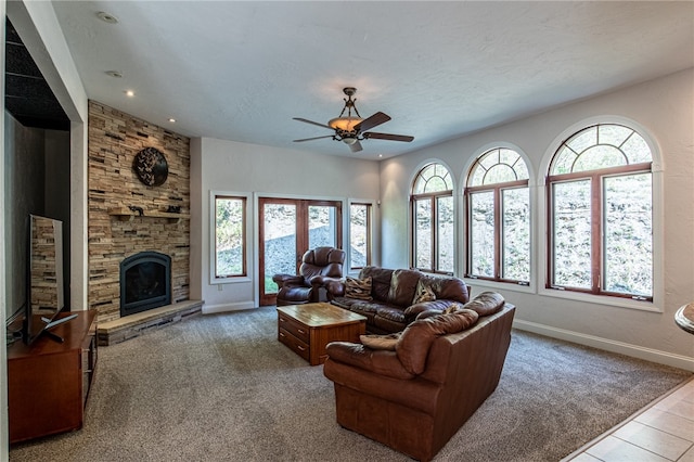 carpeted living room featuring a textured ceiling, ceiling fan, and a stone fireplace