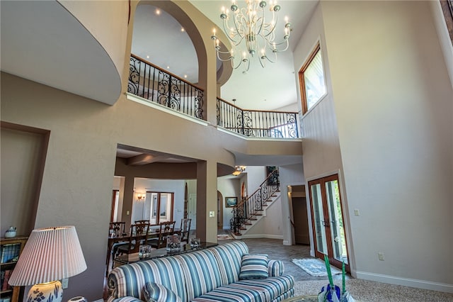 living room featuring an inviting chandelier, carpet, a towering ceiling, and plenty of natural light