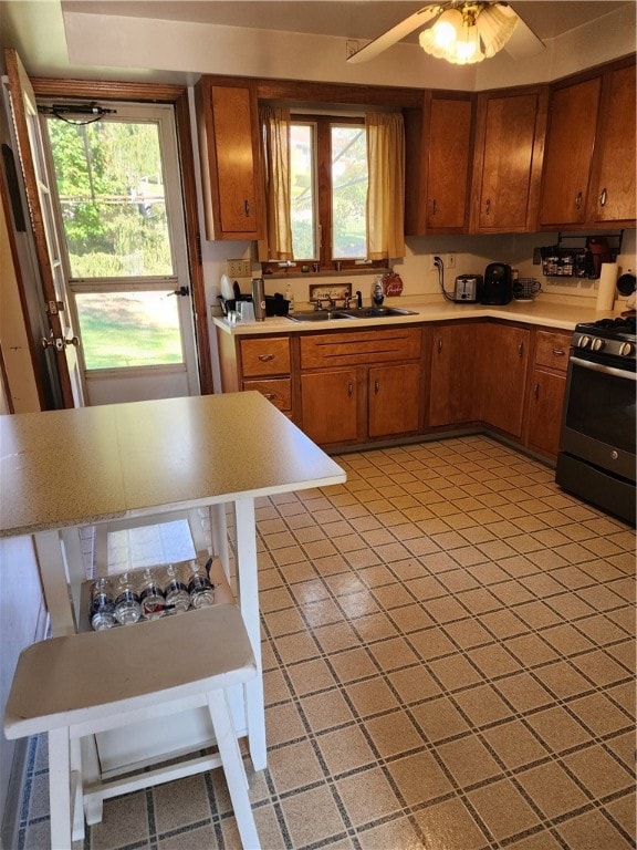 kitchen featuring gas stove, sink, and ceiling fan