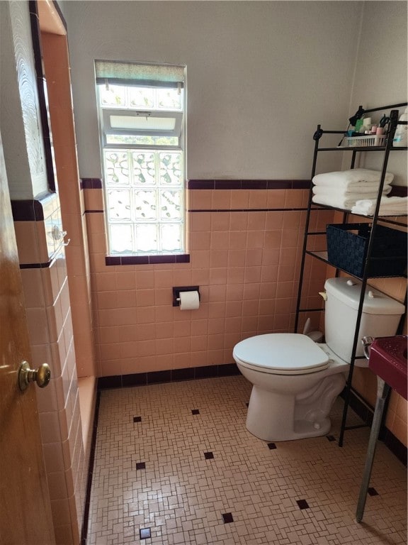 bathroom featuring tile walls and toilet