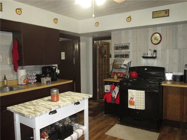 kitchen featuring dark brown cabinets, dark wood-type flooring, sink, black gas range oven, and ceiling fan