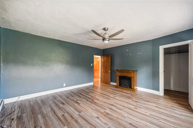 unfurnished living room featuring a baseboard heating unit, a textured ceiling, light wood-type flooring, and ceiling fan