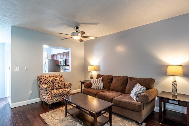 living room with ceiling fan, dark hardwood / wood-style floors, and a textured ceiling