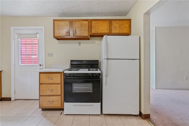 kitchen featuring light colored carpet, white appliances, and a textured ceiling