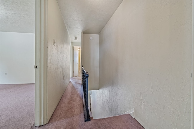 corridor with a textured ceiling and carpet flooring