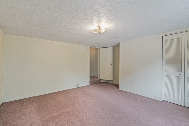 carpeted empty room with a textured ceiling