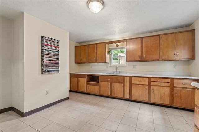 kitchen featuring light tile patterned flooring, sink, and a textured ceiling