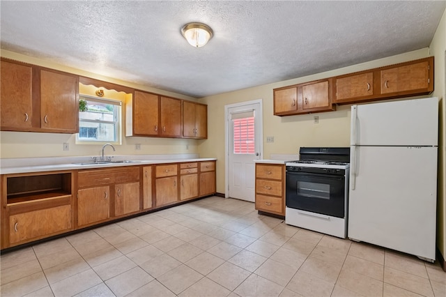 kitchen featuring light tile patterned flooring, white appliances, sink, and a textured ceiling