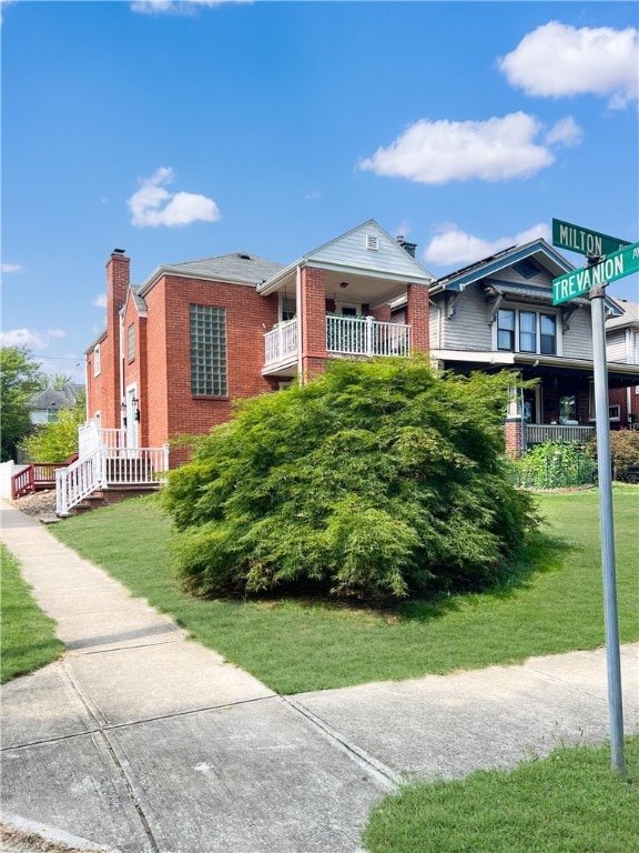 view of front of house with a front yard and a balcony