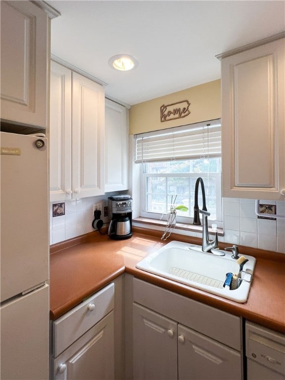 kitchen with white cabinetry, sink, white fridge, and backsplash