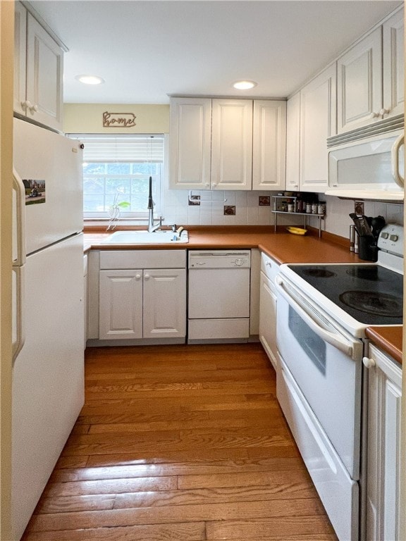 kitchen featuring white cabinets, white appliances, and light wood-type flooring