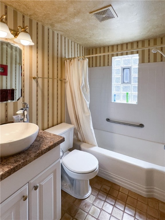 full bathroom featuring a textured ceiling, vanity, toilet, and shower / bath combo with shower curtain