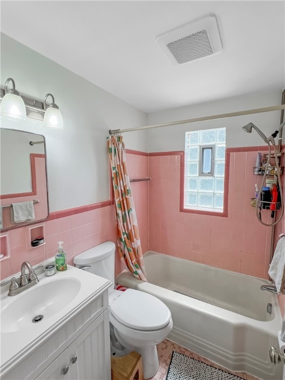 full bathroom featuring tile walls, shower / bath combo with shower curtain, vanity, tile patterned flooring, and toilet