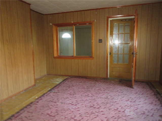 unfurnished room featuring light carpet and wood walls