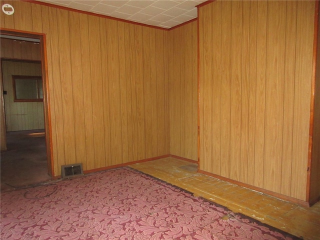 carpeted spare room featuring wood walls