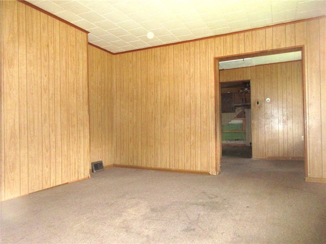 spare room featuring wood walls and light carpet