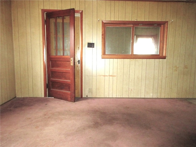 carpeted spare room featuring wooden walls