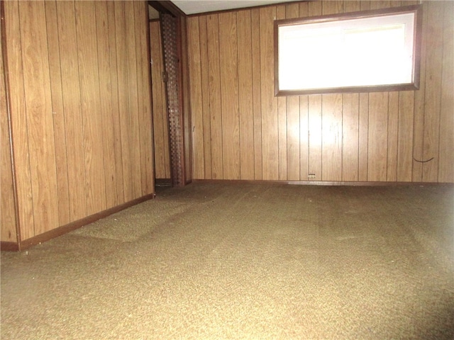 empty room featuring light colored carpet and wood walls