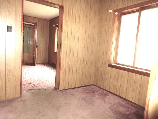 carpeted empty room featuring wood walls