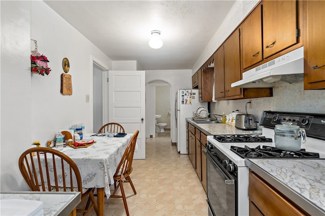 kitchen featuring white refrigerator, sink, and gas stove