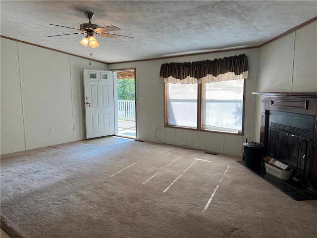 unfurnished living room featuring a textured ceiling, carpet flooring, ornamental molding, and ceiling fan