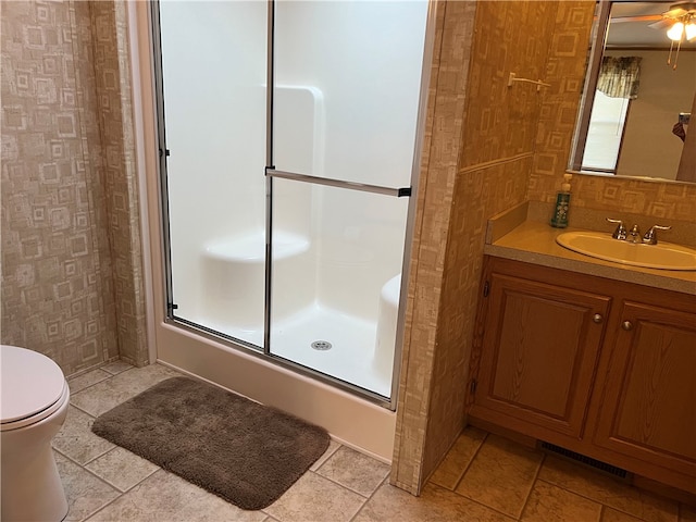 bathroom featuring tile patterned flooring, walk in shower, ceiling fan, vanity, and toilet