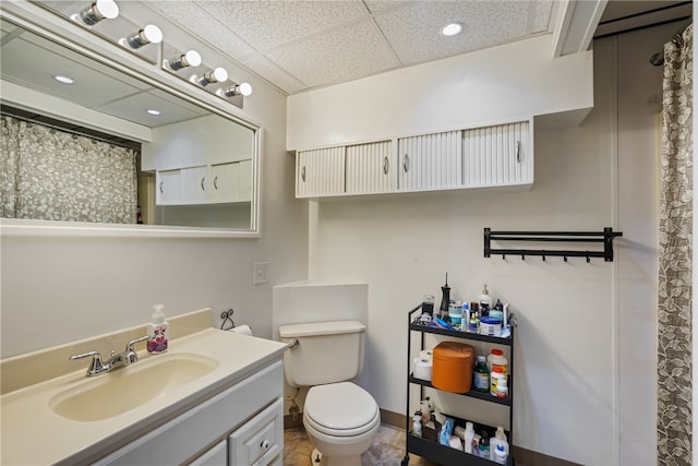 bathroom with vanity, a drop ceiling, toilet, and tile patterned floors