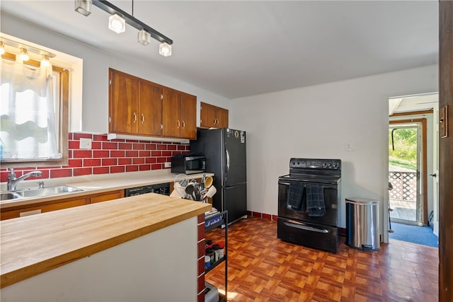 kitchen with decorative backsplash, dark parquet floors, black appliances, track lighting, and sink