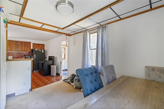 interior space with dark parquet flooring, a drop ceiling, and washer / dryer