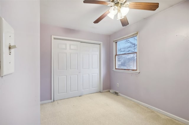 unfurnished bedroom with ceiling fan, light carpet, and a closet