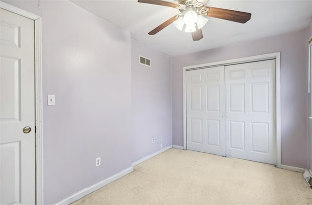 unfurnished bedroom featuring ceiling fan, light colored carpet, and a closet