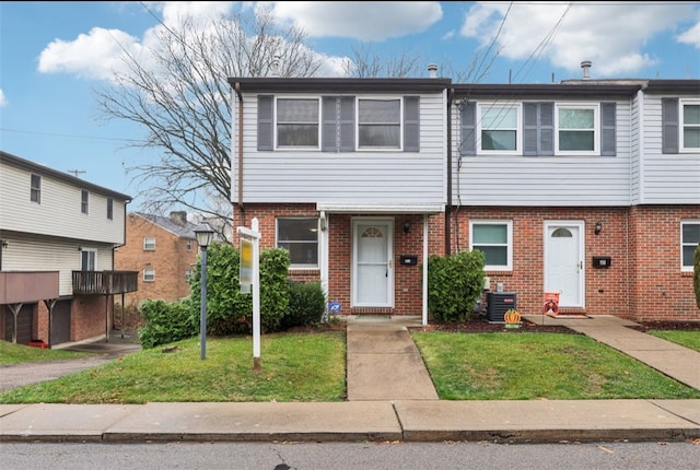 townhome / multi-family property with central AC unit and a front yard