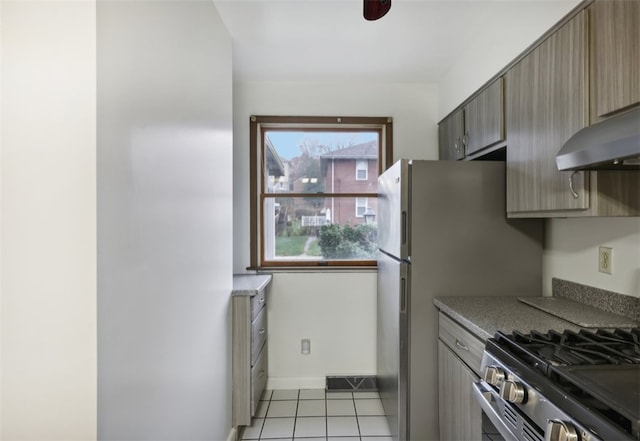 kitchen with light tile patterned floors, range hood, and stainless steel range with gas stovetop