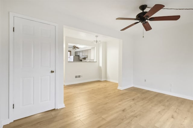 unfurnished living room with ceiling fan with notable chandelier and light wood-type flooring