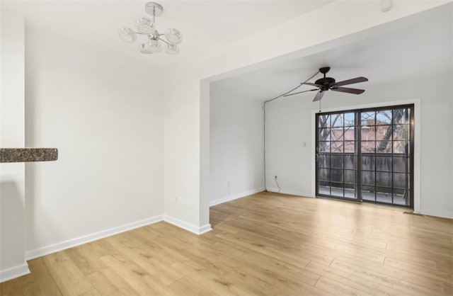 unfurnished living room featuring ceiling fan with notable chandelier and light wood-type flooring