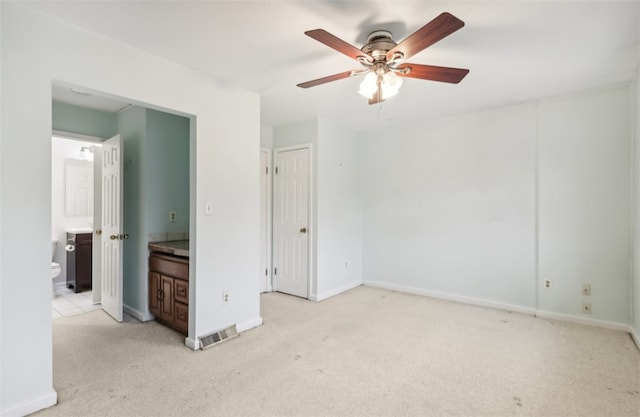 unfurnished bedroom featuring ensuite bathroom, ceiling fan, and light colored carpet