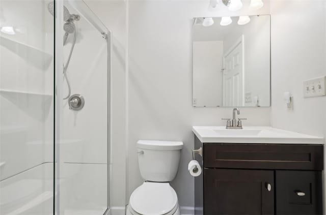 bathroom featuring vanity, toilet, and a shower with door