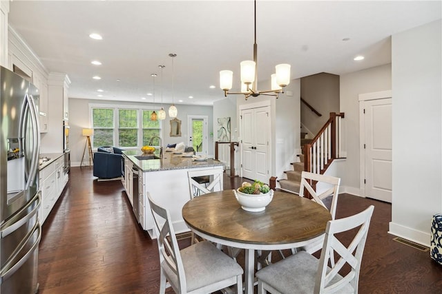 dining space featuring dark hardwood / wood-style floors, sink, and a chandelier