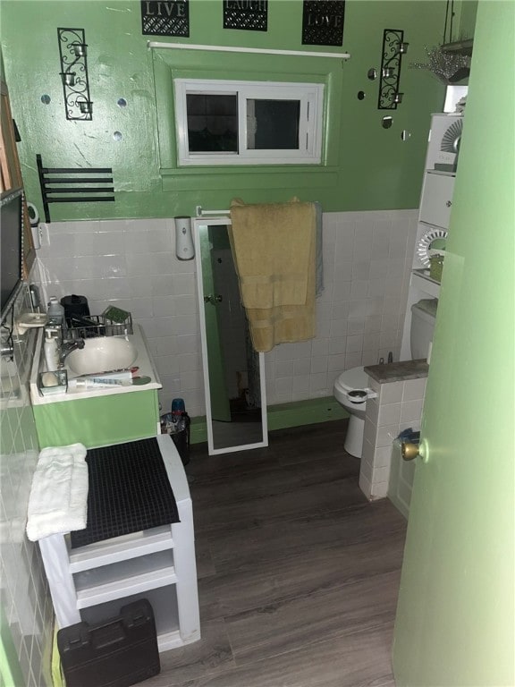 bathroom featuring tile walls, hardwood / wood-style flooring, vanity, and toilet