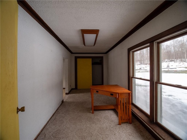 hallway with light colored carpet, ornamental molding, and a textured ceiling