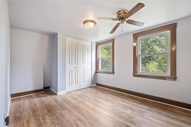 unfurnished bedroom featuring multiple windows, ceiling fan, a closet, and light hardwood / wood-style floors