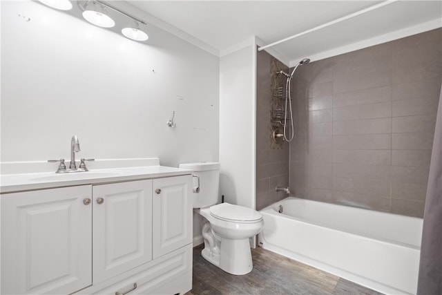 full bathroom with hardwood / wood-style floors, vanity, crown molding, tiled shower / bath combo, and toilet