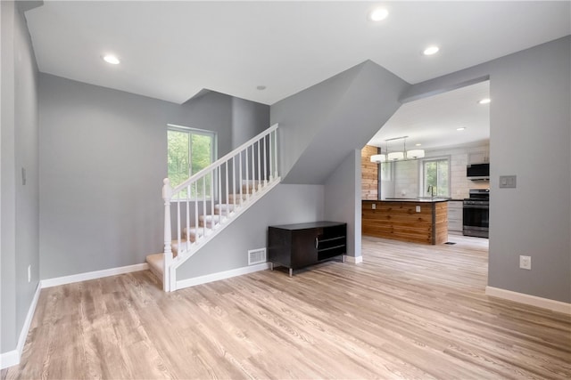 unfurnished living room featuring light wood-type flooring, sink, and a chandelier