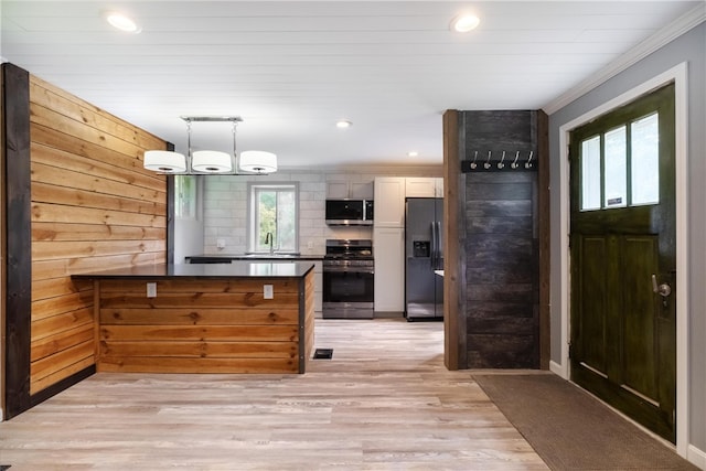 kitchen with appliances with stainless steel finishes, sink, light hardwood / wood-style flooring, white cabinetry, and hanging light fixtures