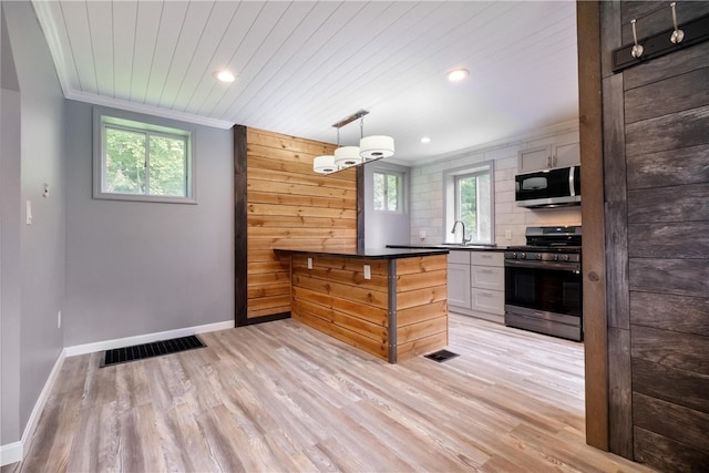 kitchen featuring pendant lighting, white cabinetry, stainless steel appliances, and light hardwood / wood-style flooring