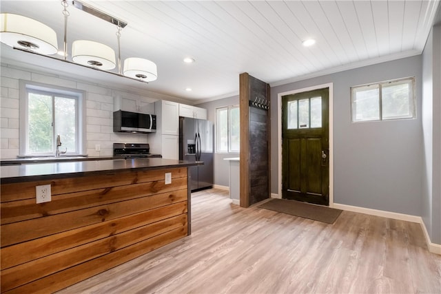 kitchen with pendant lighting, white cabinets, sink, light wood-type flooring, and appliances with stainless steel finishes