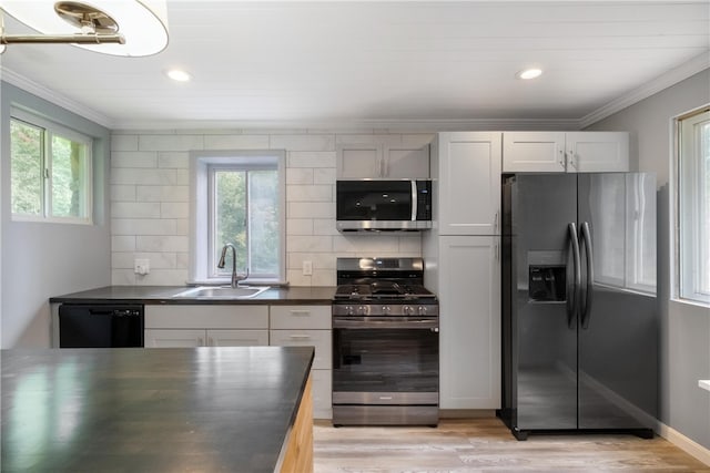 kitchen with appliances with stainless steel finishes, backsplash, sink, light hardwood / wood-style floors, and white cabinetry